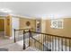 Upstairs hallway with wood railing overlooking the foyer and staircase with overhead chandelier at 108 Donovan Ave, Locust Grove, GA 30248