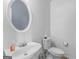 Clean half bathroom with a white sink, toilet, and a round mirror on the wall at 1235 Labonte Pkwy, Mcdonough, GA 30253