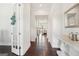 Long hallway with dark hardwood floors and white trim offering a glimpse into the light-filled living area at 401 Hallman Pl, Peachtree City, GA 30269