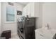 A modern laundry room with a sink, front loading washer and dryer, and overhead cabinets for storage at 401 Hallman Pl, Peachtree City, GA 30269
