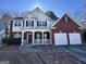 Inviting two-story home with brick accents, a covered porch, and a well-manicured front lawn at 5725 Lake Windsor Pkwy, Buford, GA 30518