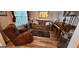 Cozy living room featuring wood floors, comfortable seating, and natural light from the window at 5725 Lake Windsor Pkwy, Buford, GA 30518