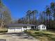 Well-maintained white home with a two-car garage and a paved driveway on a sunny day at 621 Hood Rd, Stockbridge, GA 30281