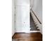 Hallway with hardwood floors, white door, and carpeted stairs with a wooden handrail at 9135 Selborne Ln, Chattahoochee Hills, GA 30268