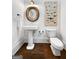 Stylish powder room with pedestal sink, round wood-framed mirror, and decor at 9135 Selborne Ln, Chattahoochee Hills, GA 30268