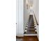 Staircase with carpet runner, wooden handrail, and white risers with wall lighting at 9135 Selborne Ln, Chattahoochee Hills, GA 30268