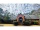 Stately brick home with an arched front entrance, surrounded by mature trees and a well-maintained lawn under a cloudy sky at 9255 Betony Wood Trl, Jonesboro, GA 30236