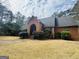 Charming one-story brick home featuring a well-manicured lawn, mature trees, and a welcoming arched entryway on a cloudy day at 9255 Betony Wood Trl, Jonesboro, GA 30236