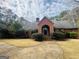 Beautifully landscaped brick home with an arched entrance and a circular driveway, set amidst mature trees on a cloudy day at 9255 Betony Wood Trl, Jonesboro, GA 30236