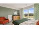 Stylish bedroom with a large window, green accent wall, wood dresser, and comfortable orange chair at 588 Parnassus Road, Locust Grove, GA 30248