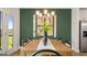 Bright dining area with a view to the outdoors, complemented by a contemporary light fixture and green accent wall at 588 Parnassus Road, Locust Grove, GA 30248