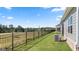 Backyard featuring well-maintained grass, black iron fence, and an air conditioning unit along the side of the house at 600 Parnassus Rd, Locust Grove, GA 30248