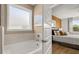 Bathroom with a large soaking tub, tile surround, and obscured glass window, open to the primary bedroom at 600 Parnassus Rd, Locust Grove, GA 30248