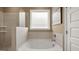 Bathroom showing a large soaking tub with shower head, tiled surround, and obscured glass window at 600 Parnassus Rd, Locust Grove, GA 30248