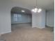 Open-concept living room featuring neutral paint, plush carpet, and an arched doorway with a decorative light fixture at 3355 Brookside Ln, Jonesboro, GA 30236