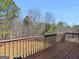 View of the wooden deck with railing overlooking a yard with mature trees and a blue sky at 195 Brighton Dr, Covington, GA 30016