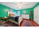 Inviting bedroom featuring vibrant green walls, hardwood floors, and a white-framed bed with colorful accents at 10175 Point View Dr, Jonesboro, GA 30238