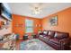 Cozy living room with vibrant orange walls, hardwood floors, and comfortable leather seating at 10175 Point View Dr, Jonesboro, GA 30238