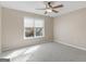 Bright bedroom features neutral walls, plush carpet, ceiling fan, and window with outside view at 231 Ashley Trace Dr, Locust Grove, GA 30248
