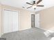 Bedroom features neutral walls, plush carpet, ceiling fan, closet, and doorway at 231 Ashley Trace Dr, Locust Grove, GA 30248