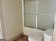 Bathroom featuring a tub-shower combo with a sliding glass door and a white toilet at 232 Darwish Dr, Mcdonough, GA 30252