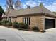 View of a brick home with a dark garage door, surrounded by lush landscaping at 232 Darwish Dr, Mcdonough, GA 30252