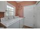 Bright laundry room with checkered wallpaper, white washer and dryer, and a window at 152 Wexford Ct, Stockbridge, GA 30281