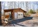 Detached garage with a lean-to, featuring a white door and surrounding wooded area at 1225 Pitts Chapel E, Newborn, GA 30056