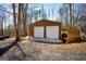 Metal outbuilding with two roll-up doors, set in a wooded area with a gravel driveway at 1225 Pitts Chapel E, Newborn, GA 30056