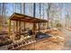 Open-air shed with stacked wood, ladder, and tools, set in a wooded backyard at 1225 Pitts Chapel E, Newborn, GA 30056