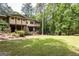 Back view of the property showcasing a well-manicured lawn and wooded scenery at 4421 Paradise Cir, Vinings, GA 30339