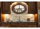 A kitchen with custom cabinets and a stone backsplash is illuminated by lights under the cabinets and an oval window at 4421 Paradise Cir, Vinings, GA 30339