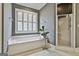 Bathroom featuring a soaking tub, plantation shutters, decorative plant, and walk-in shower at 605 St. Charles Pl, Fayetteville, GA 30215