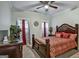 Bedroom with decorative bed, red pillows and covers, ceiling fan, and windows with patterned curtains at 3434 Estels Ln, Conyers, GA 30013