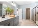 This well-lit bathroom features double sinks, grey cabinetry, tile floors, and a glass shower at 10459 Trellis Lane (Lot 27), Hampton, GA 30228