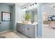 This inviting bathroom has double sinks, updated lighting, blue walls, and tile floors at 10459 Trellis Lane (Lot 27), Hampton, GA 30228