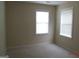 Neutral carpeted bedroom featuring two bright windows with white blinds at 358 Southgate Dr, Locust Grove, GA 30248