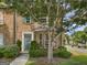 Charming brick townhome features a green front door, lush landscaping, and a mature shade tree in a residential neighborhood at 11403 South Grove Dr, Hampton, GA 30228
