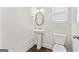 Bathroom features a pedestal sink, elongated toilet, oval mirror, modern fixtures and hardwood floors at 11192 Cornerstone Way, Hampton, GA 30228