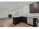 Open-concept kitchen featuring dark wood cabinets, granite counters, and stainless appliances, open to the living room at 11192 Cornerstone Way, Hampton, GA 30228
