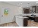 Bright kitchen featuring stainless appliances, granite countertops, dark wood cabinets, hardwood floors and backyard access at 11192 Cornerstone Way, Hampton, GA 30228