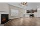 Spacious living room with a fireplace, hardwood floors, a ceiling fan, and an open concept leading to the kitchen at 11192 Cornerstone Way, Hampton, GA 30228