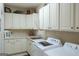 Well-organized laundry room with white cabinets, sink, and modern washer and dryer at 168 Maple Grove Ter, Peachtree City, GA 30269