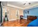 Bright bedroom with a blue accent wall, hardwood floors, and connected bath at 124 Shelton Dr, Mcdonough, GA 30252