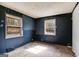 Dark blue bedroom with two windows and damaged walls and floors at 2864 S 100 Hwy, Bowdon, GA 30108