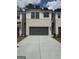 New townhome featuring a gray two-car garage, painted brick, modern black trim and shutters, and concrete driveway at 984 Sutherland Ln # 31, Lawrenceville, GA 30043