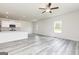 Spacious living room with gray wood-look floors, large window, ceiling fan, and kitchen view at 439 Prescott Way, Villa Rica, GA 30180