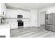 Bright kitchen with stainless steel appliances, white cabinets, granite countertops, and gray wood-look flooring at 443 Prescott Way, Villa Rica, GA 30180