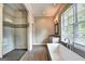 Bright bathroom featuring a glass shower, soaking tub, sleek fixtures, and a view to the outdoors at 337 Lakeshore Dr, Berkeley Lake, GA 30096