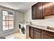 Well-lit laundry room with front-load washer/dryer and granite countertop, complemented by dark wood cabinets at 337 Lakeshore Dr, Berkeley Lake, GA 30096